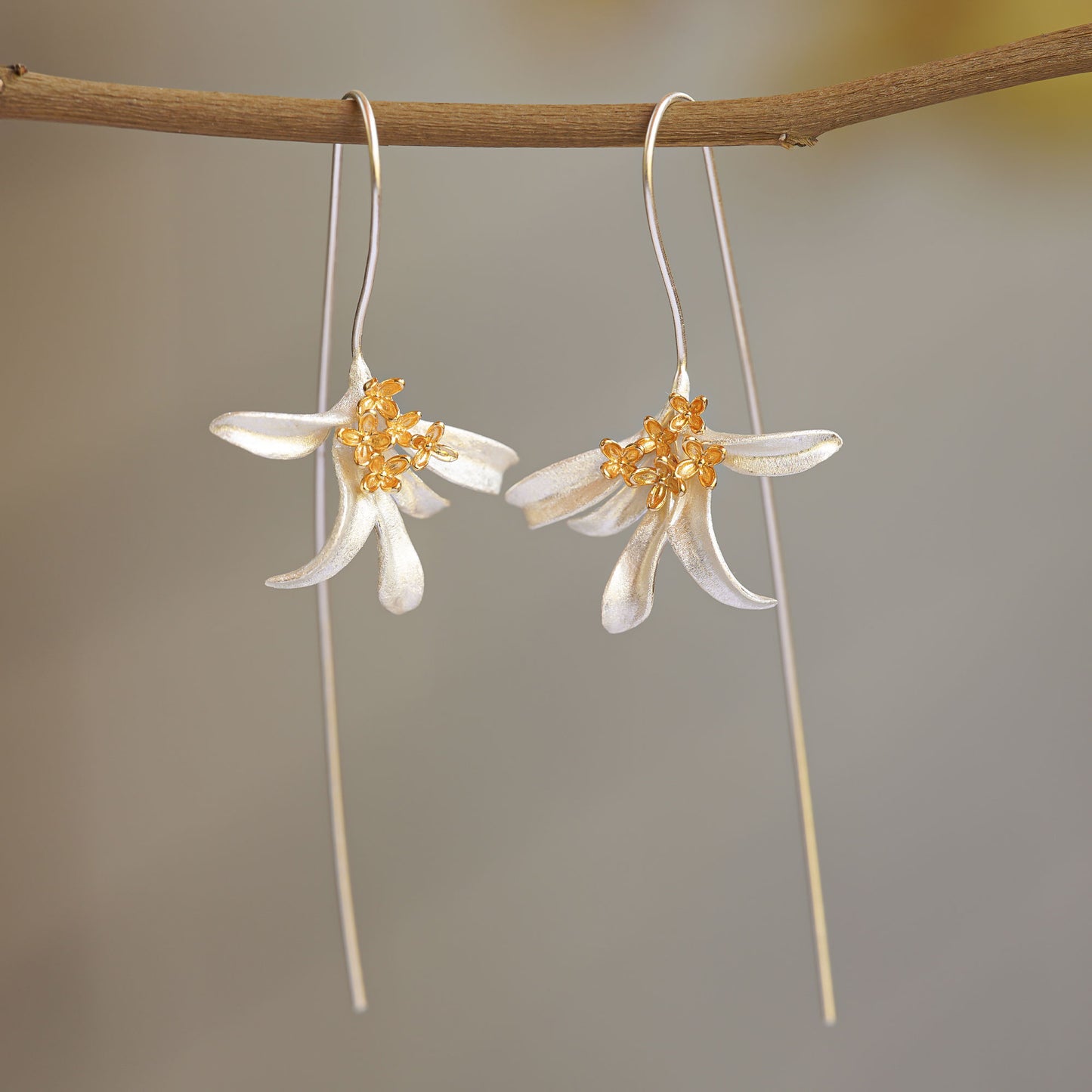 A pair of osmanthus earrings hanging from a tree branch