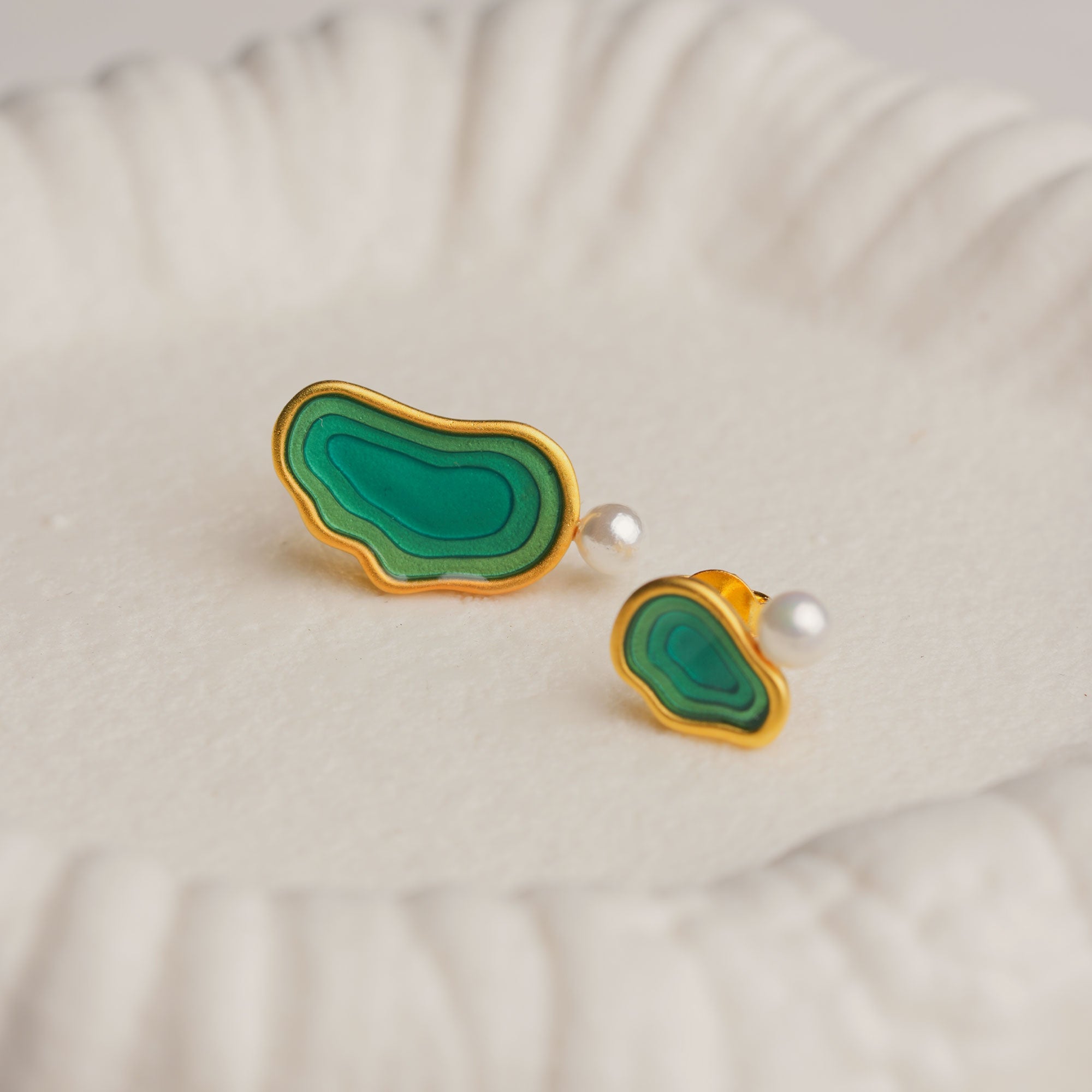 Asymmetrical green resin pearl stud earrings on white background