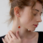 Festive holiday earrings with red agate and gold bow on model