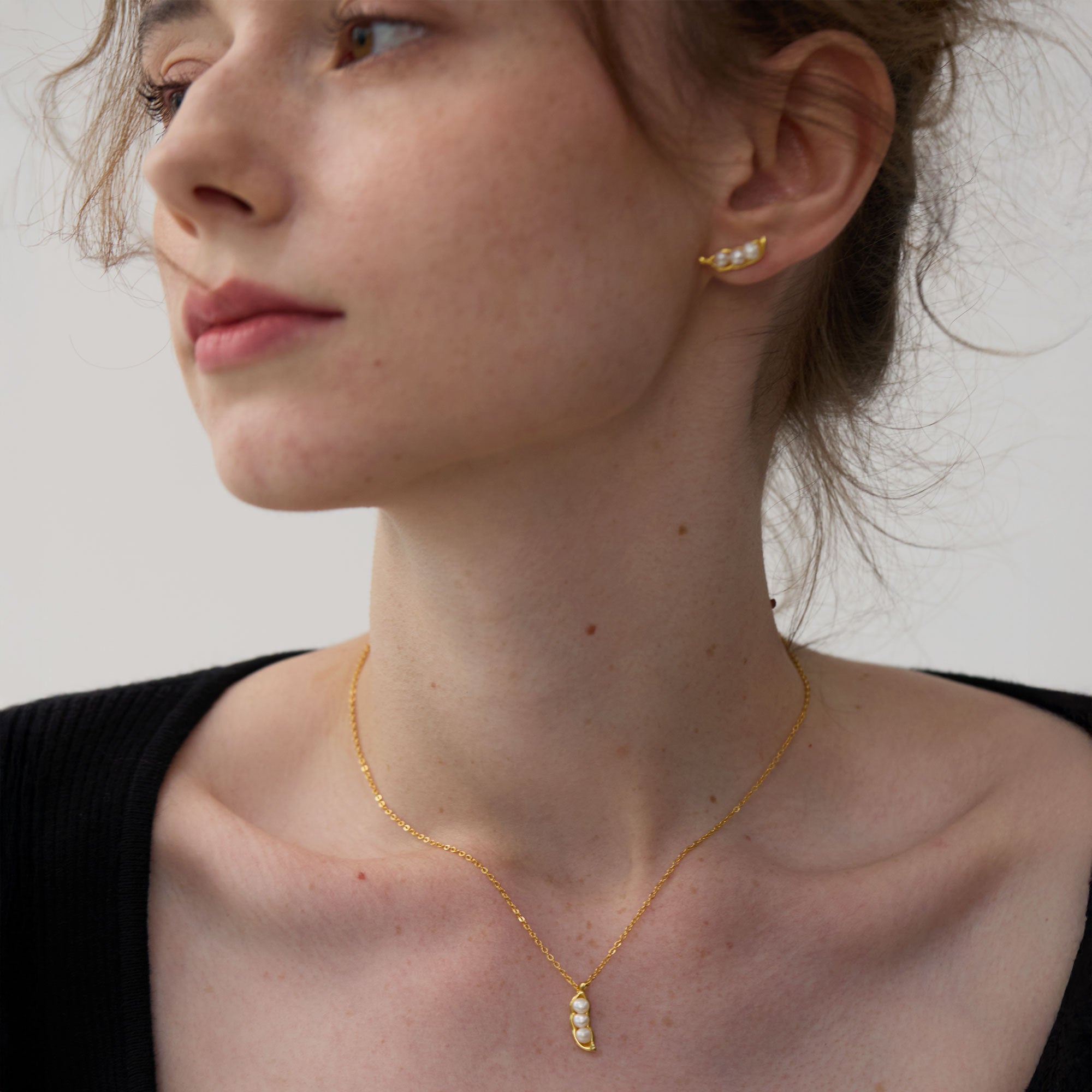 Gold pea pod necklace with three freshwater pearls, handcrafted in 925 silver gilt, worn close to the collarbone.