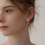 Gold and silver carrot earrings with silver leaf details on model