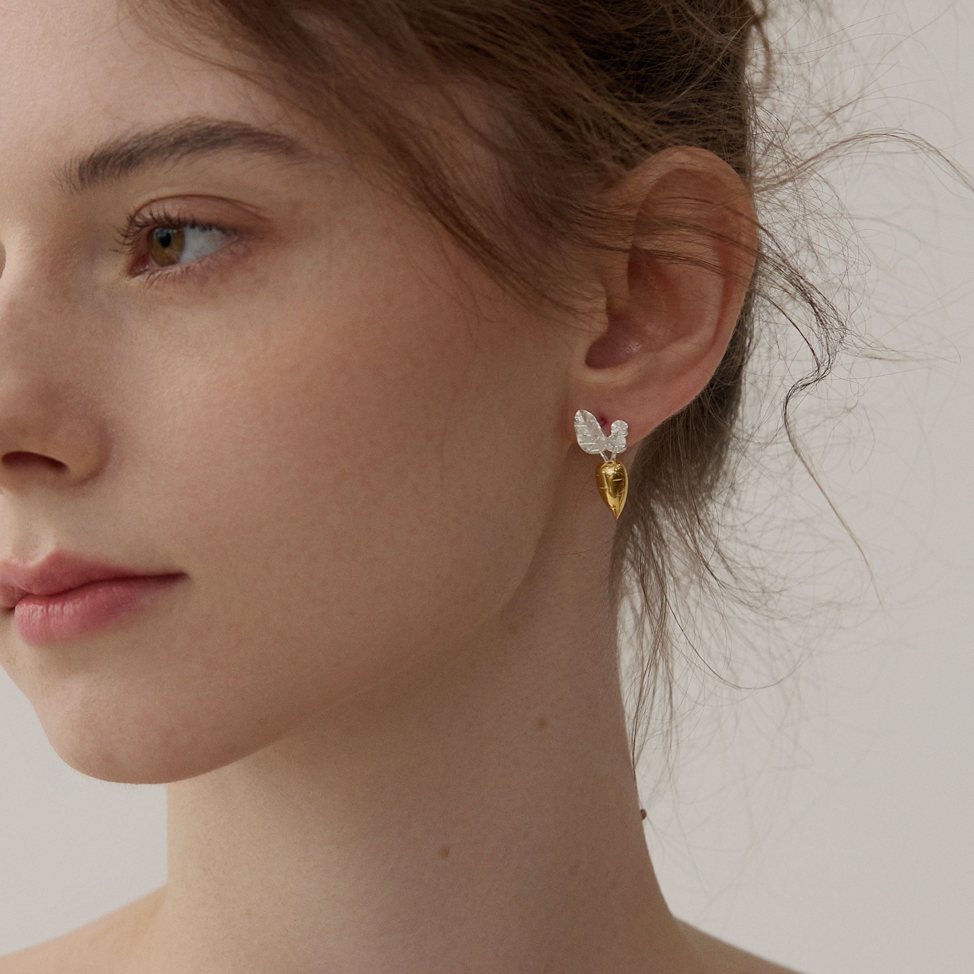 Gold and silver carrot earrings with silver leaf details on model
