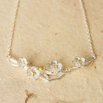Plum blossom necklace displayed on neutral background