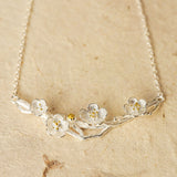 Plum blossom necklace displayed on neutral background