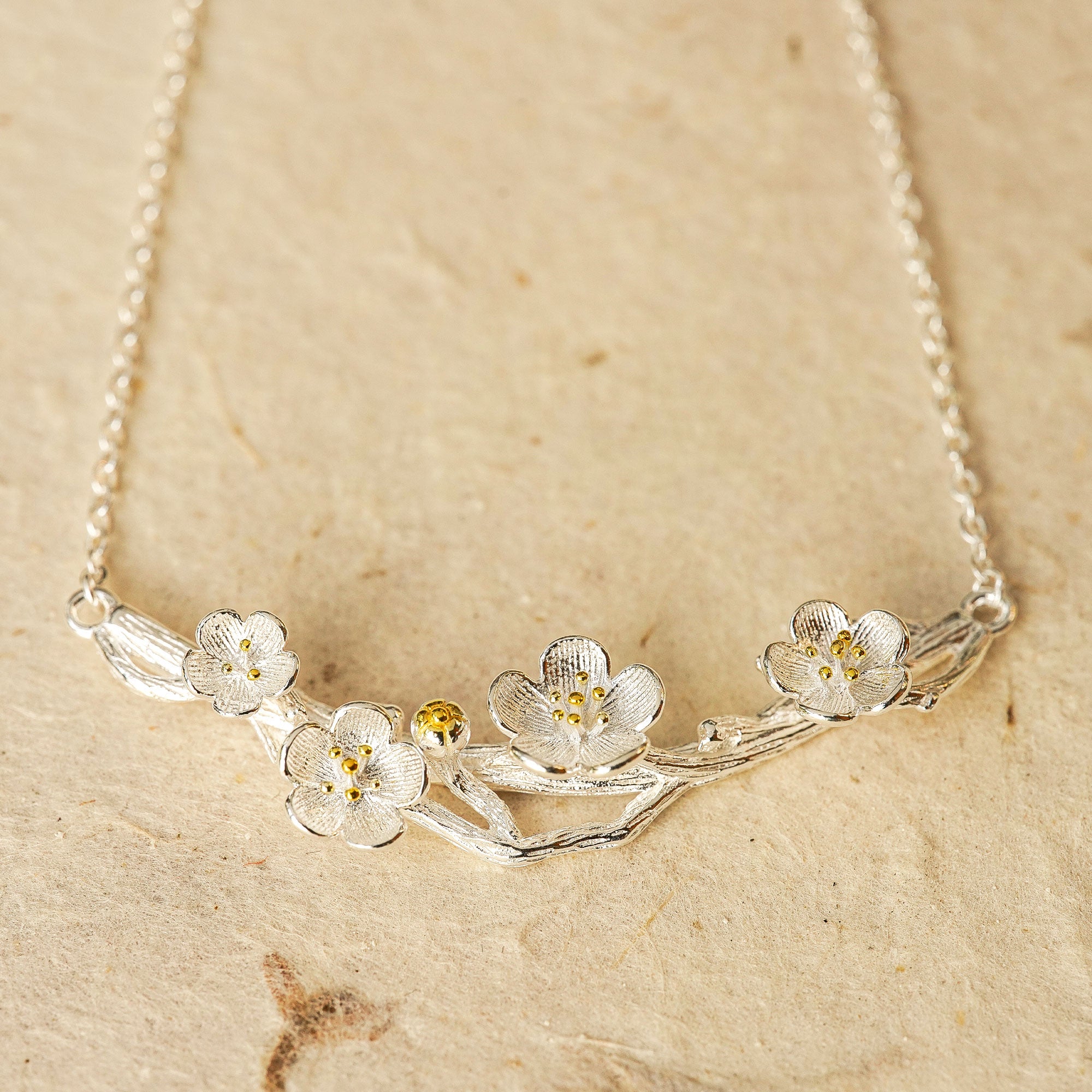 Plum blossom necklace displayed on neutral background