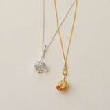 Sterling silver and gold tulip necklaces displayed on jewelry board