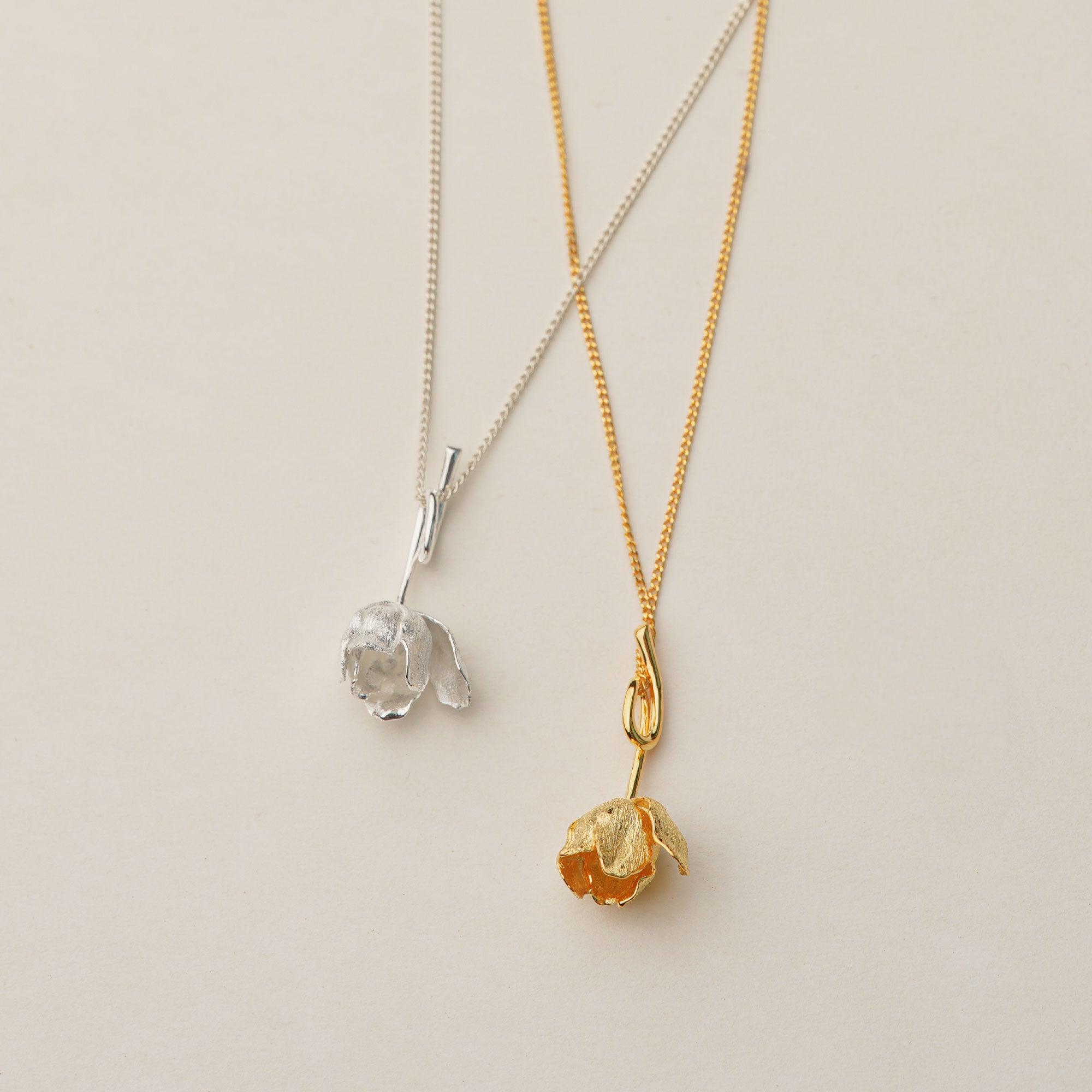 Sterling silver and gold tulip necklaces displayed on jewelry board