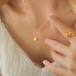 Woman wearing gold tulip necklace with matching ring