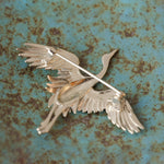 Crane bird brooch displayed on neutral background