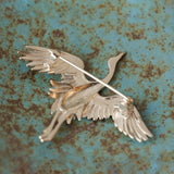 Crane bird brooch displayed on neutral background
