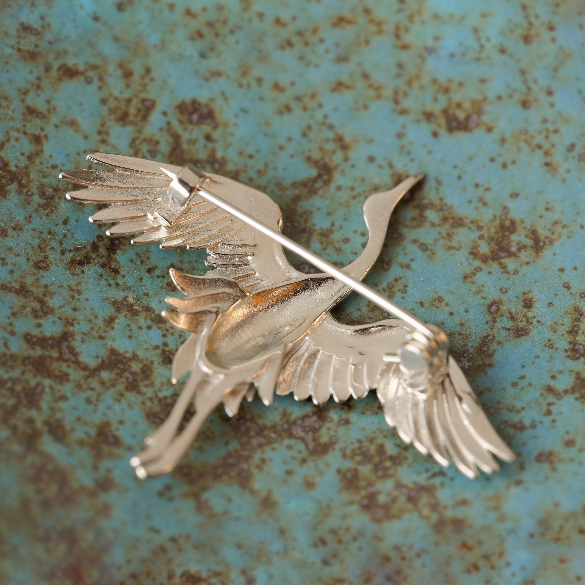 Crane bird brooch displayed on neutral background