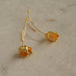 Close-up of gold tulip flower earrings lying flat, highlighting organic petal texture and handmade finish