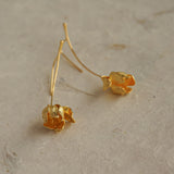 Close-up of gold tulip flower earrings lying flat, highlighting organic petal texture and handmade finish