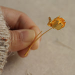 Hand holding a gold tulip flower earring showcasing petal texture and artisanal details