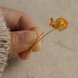 Hand holding a gold tulip flower earring showcasing petal texture and artisanal details