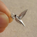 Hand holding silver hummingbird earrings close-up