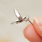 Hand holding tiny hummingbird earrings close-up