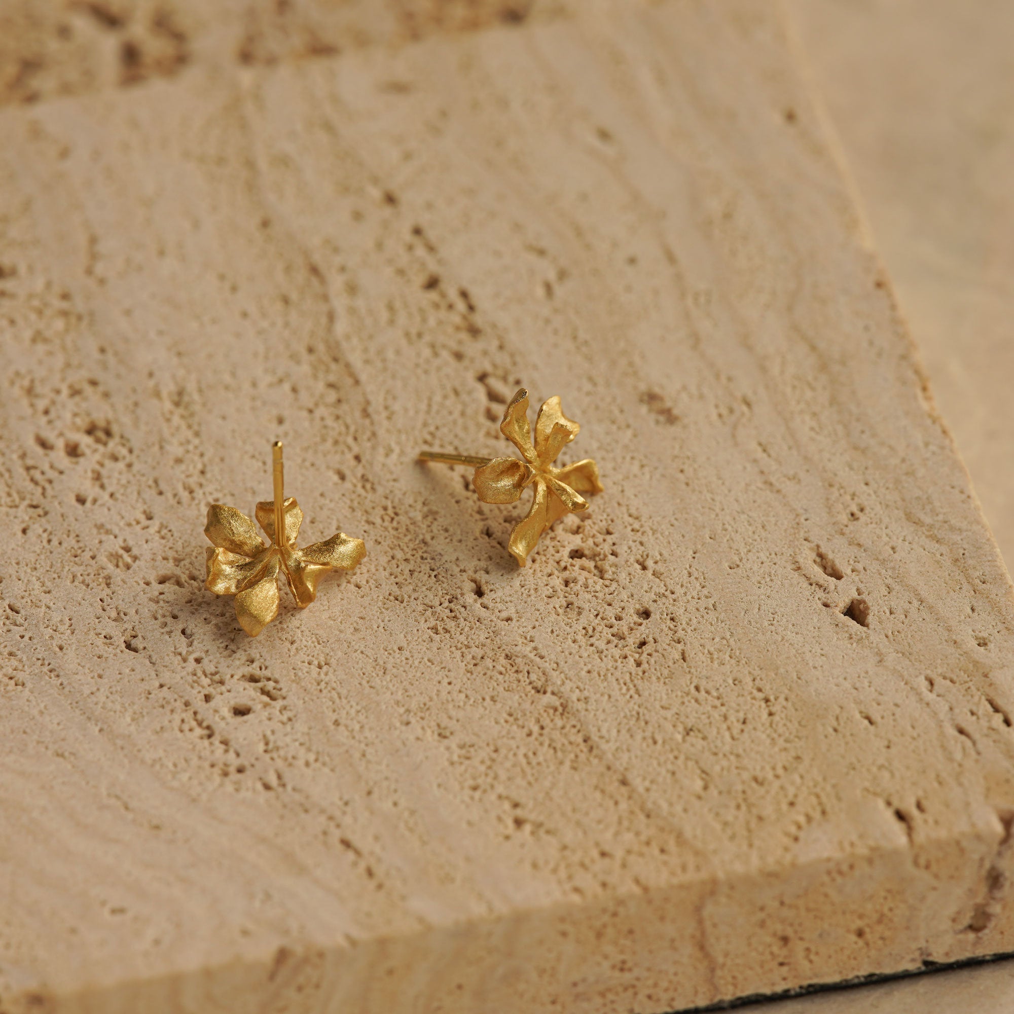 Iris stud earrings on a neutral product background