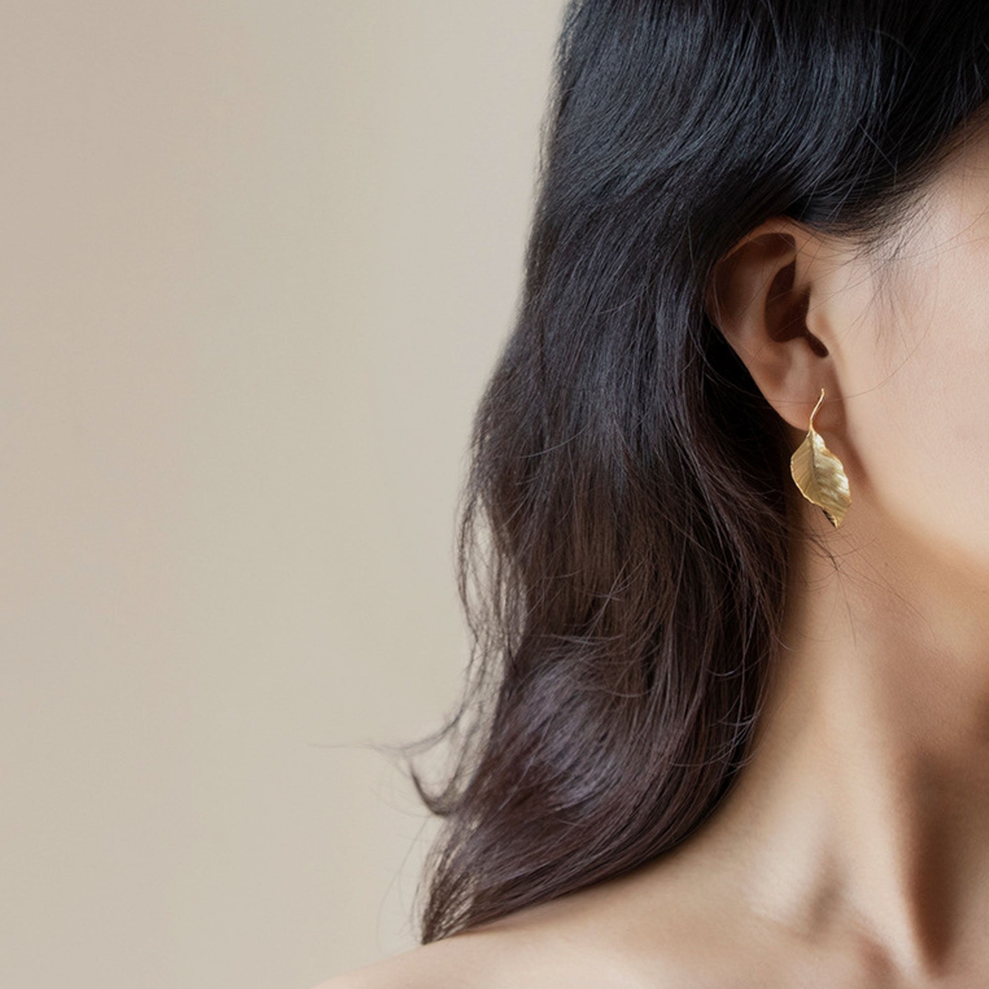Leaf drop earrings on neutral product background