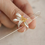Hand holding an osmanthus flower earring close-up
