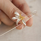 Hand holding an osmanthus flower earring close-up