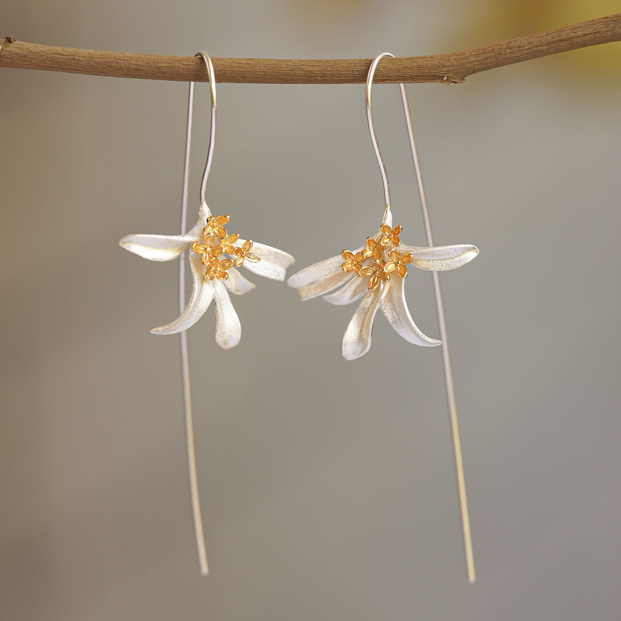 Osmanthus flower earrings hanging from a tree branch