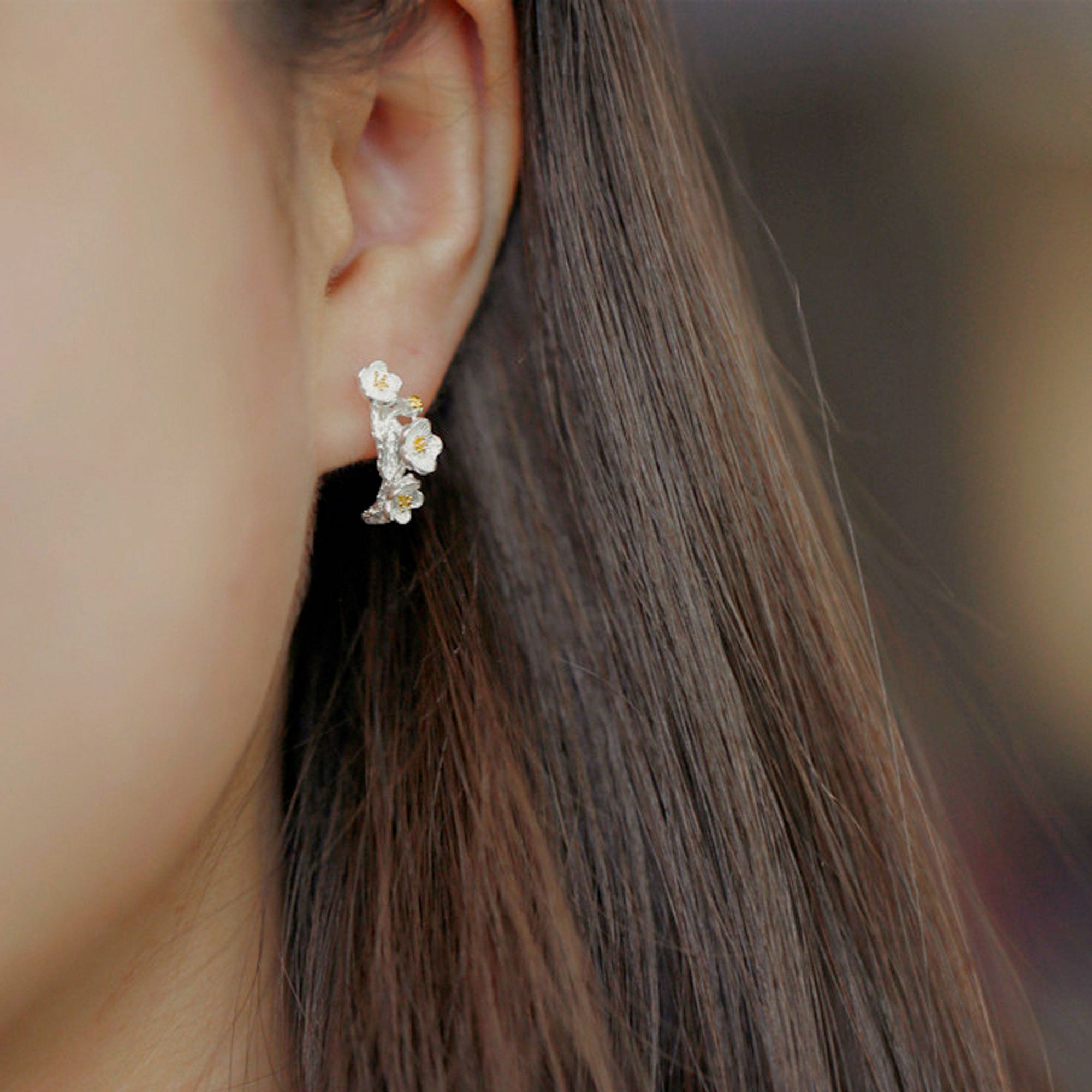 Plum blossom earrings on a neutral product background