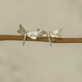 Silver dragonfly stud earrings displayed on a wooden branch