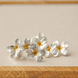 Silver flower earrings on a neutral product background