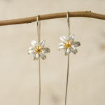 Front view of silver lily flower earrings with long hook wires