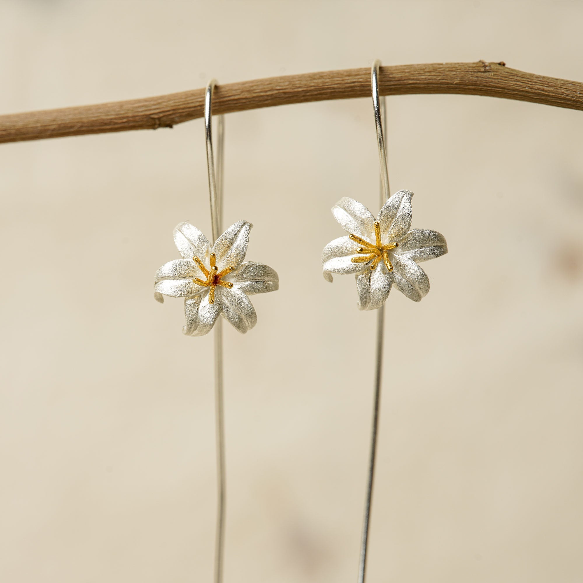 Front view of silver lily flower earrings with long hook wires