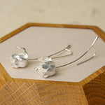 Silver tulip earrings displayed on a wooden tray, highlighting handcrafted flower details