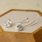 Silver tulip earrings displayed on a wooden tray, highlighting handcrafted flower details