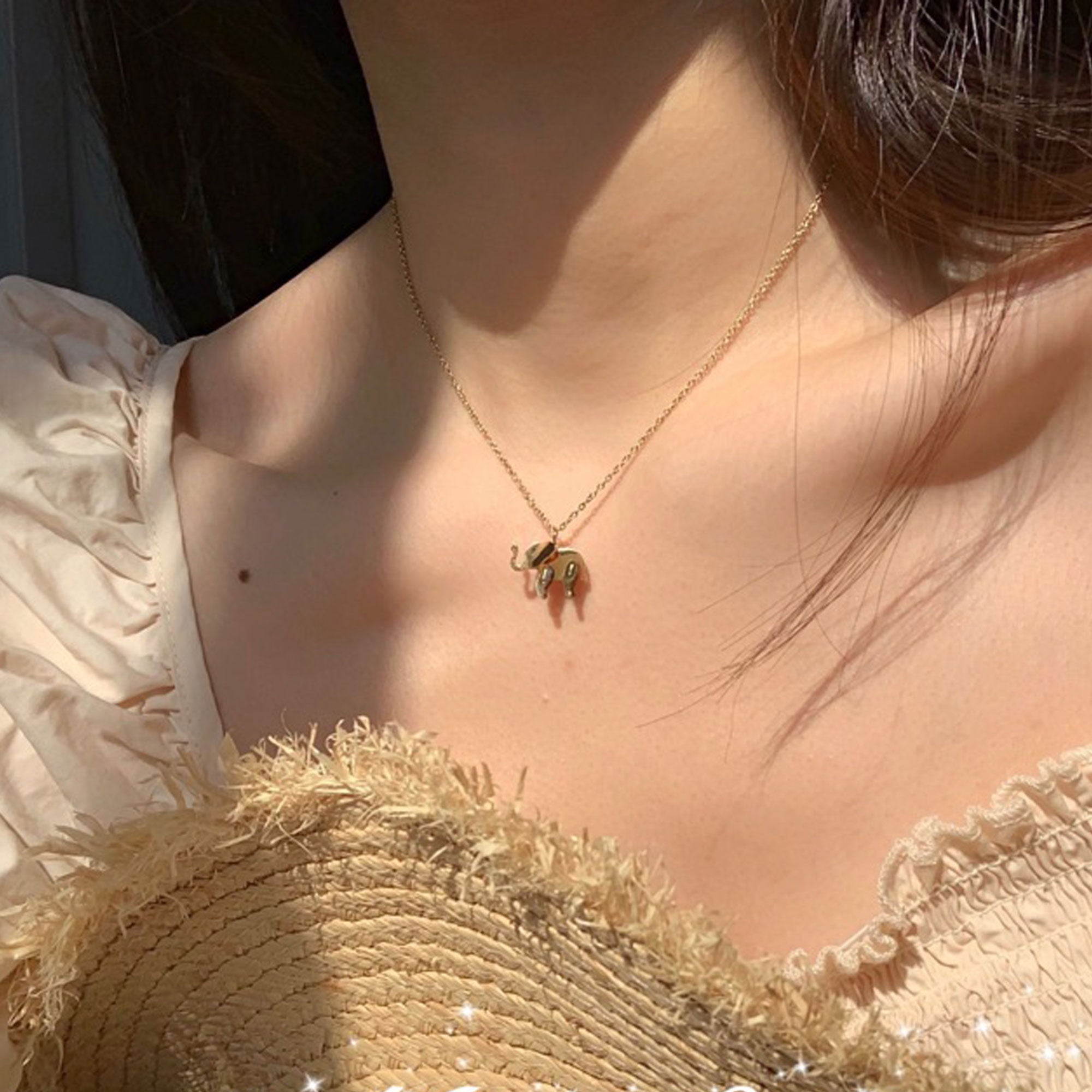 Woman wearing a gold elephant necklace with adjustable chain